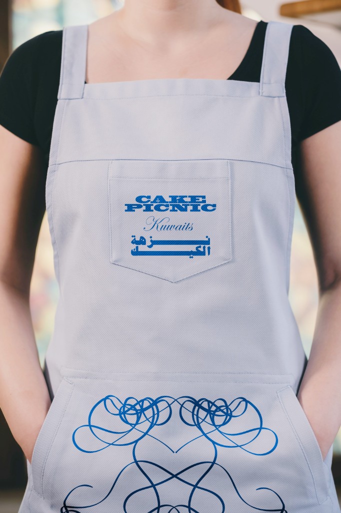 Cake Picnic apron with blue logo lockup and generative frosting ornament