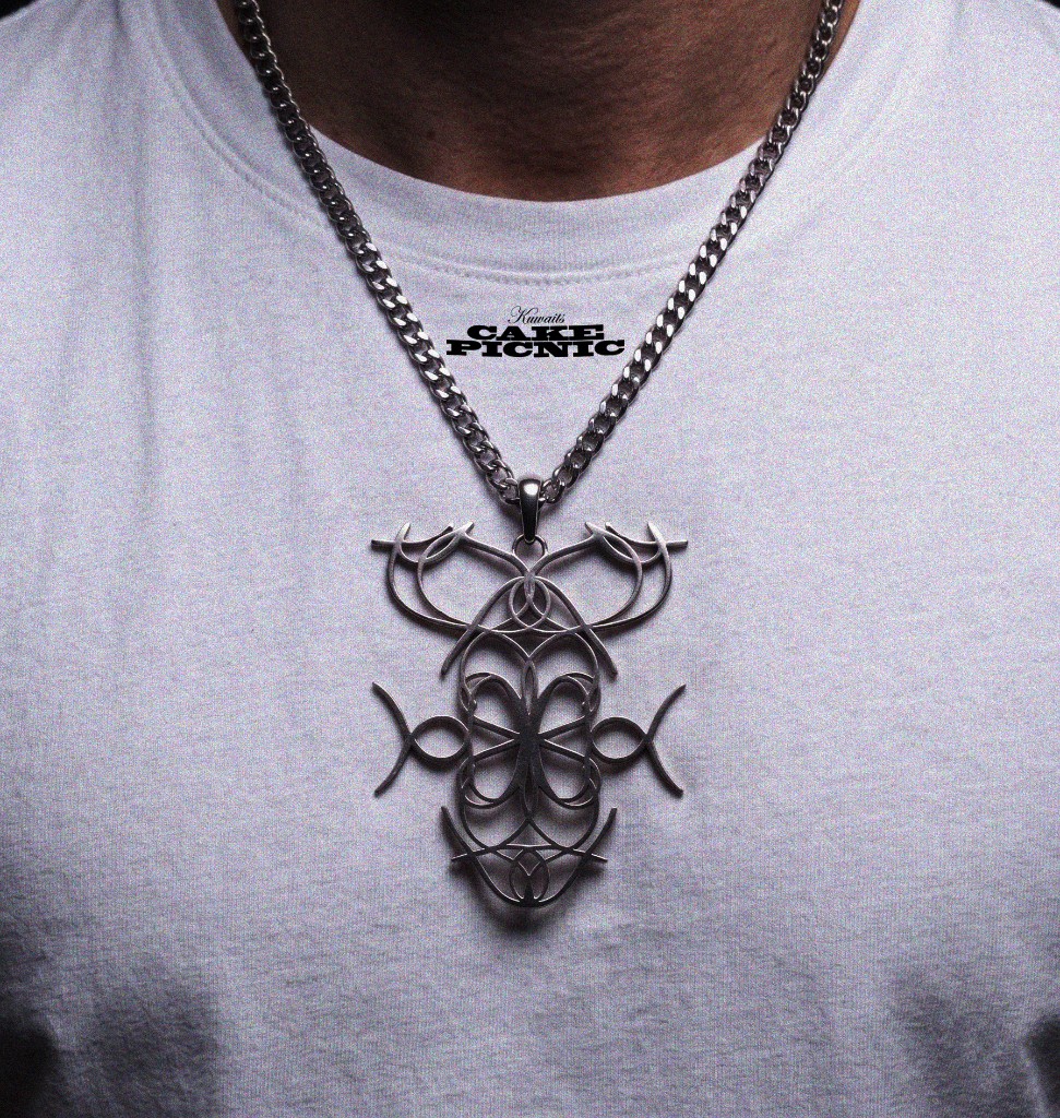 Metal Cake Picnic ornament necklace worn over a white shirt